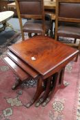 A reproduction mahogany nest of three tables