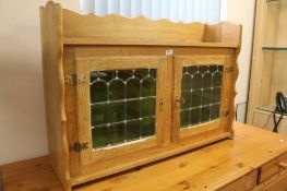 A light oak glazed wall cabinet