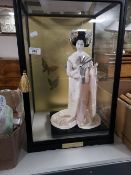 A decorative Geisha figure in display cabinet