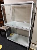 A glazed double door cabinet on wheels