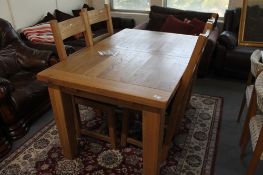 A light oak extending dining table and four ladder backed chairs