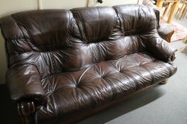 A three piece brown leather lounge suite with wooden frame