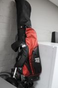 A golf bag with trolley and clubs