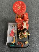 A tray of three figures of geisha on wooden stands