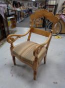 An antique pine scroll armchair