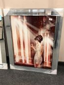 A mirrored framed picture of a lady in elegant dress