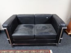 A contemporary metal framed black leather two seater settee