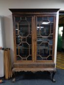 An early 20th century double door glazed display cabinet on claw and ball feet
