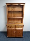 A pine kitchen dresser with cupboards and drawers beneath