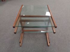 A teak glass topped table fitted with table beneath