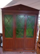 A stained pine triple door sliding door bookcase