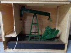 A scratch built plastic model of an oil derrick in wooden crate