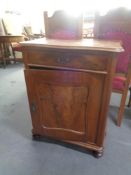 An antique mahogany single door cabinet on bun feet