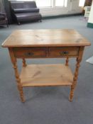 A stripped pine two drawer side table 63 cm x 42 cm x 69 cm.