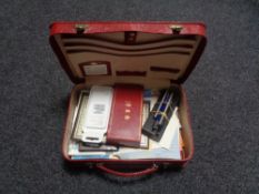 A red leather travel case containing paper ephemera, pens, note paper,