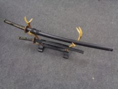 Two graduated Japanese decorative katanas on stand