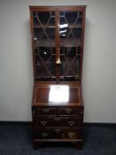 A Victorian inlaid mahogany bureau bookcase on bracket feet fitted with four drawers and brass drop