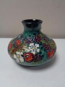 A Moorcroft baluster vase, depicting summer fruit on an emerald green ground, height 10.5 cm.
