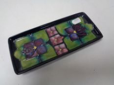 A Moorcroft shallow dish, Art Deco design on dark green ground, length 20 cm.