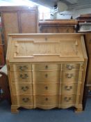 A blonde oak serpentine fronted bureau