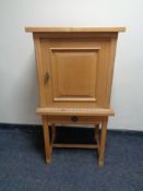 A blonde oak cabinet on raised legs