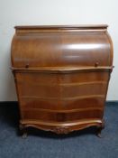 A walnut serpentine fronted barrel bureau