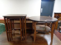 A circular mid 20th century table and a nest of three walnut tables