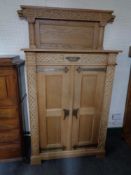A 20th century blonde oak double door cabinet in an oriental style with metal mounts