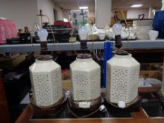 Three cream hexagonal pottery table lamps on wooden bases