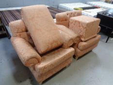 A pair of peach upholstered armchairs and a footstool