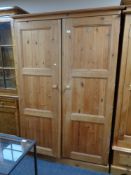A pine double door wardrobe fitted with internal drawers