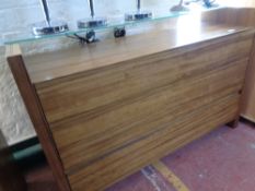 A three drawer contemporary chest with glass shelf