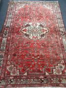 A fringed Iranian Hamadan rug on red ground
