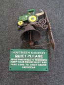 A cast iron tractor wall bracket with bell and a railway safety notice