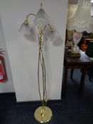 A brass three way floor lamp with glass shades