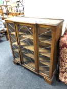 A 1930's triple door oak break fronted bookcase with leaded glass doors
