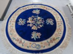 A circular fringed Chinese rug on blue ground