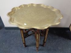 A Moorish brass topped table on folding wooden base