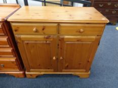 A pine double door cabinet fitted with two drawers