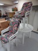 A circular white plastic garden table and four armchairs with cushions