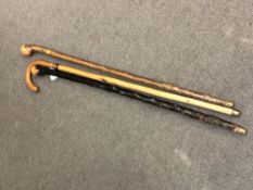 A vintage sword stick with yellow metal mount, together with two further sticks.