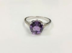 A silver dress ring set with a purple stone,