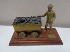 A welsh brass mining figure with cart on wooden board