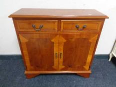 An inlaid yew wood double door cabinet fitted with two drawers above