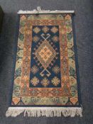 A machine made fringed hearth rug on blue ground. 132 cm x 75 cm.