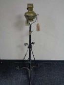 An antique wrought iron rise and fall standard lamp with brass oil lamp