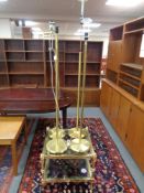 A brass and glass two tier coffee table together with four brass standard lamps