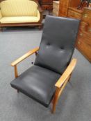 A mid century Danish teak framed adjustable armchair upholstered in black vinyl