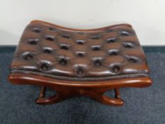 A brown buttoned leather upholstered footstool on X-frame support