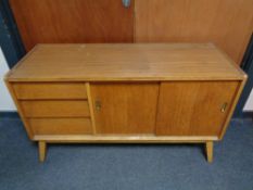 A mid century teak sliding door sideboard fitted with three drawers